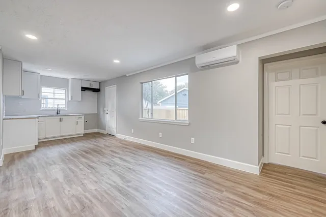 a view of an empty room with wooden floor and a window