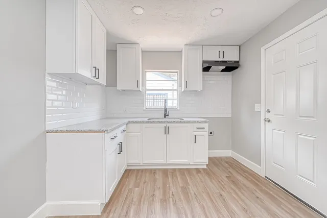 a kitchen with granite countertop white cabinets and white appliances
