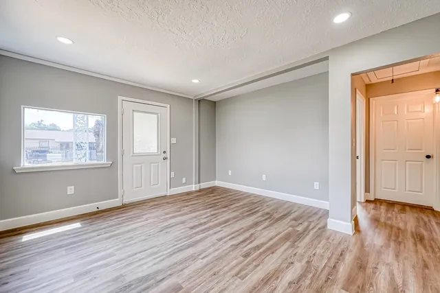 a view of an empty room with wooden floor and a window