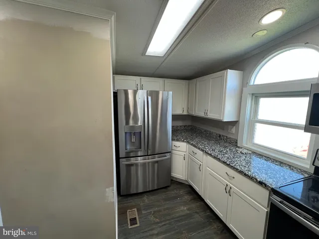 a kitchen with granite countertop a refrigerator and a sink