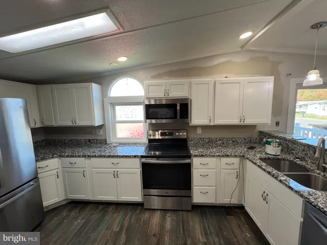 a kitchen with stainless steel appliances granite countertop a stove a sink and white cabinets
