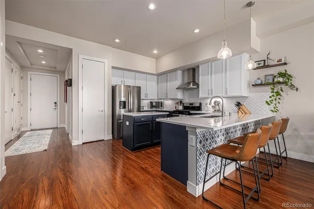 a kitchen with stainless steel appliances granite countertop a refrigerator a stove a sink dishwasher and a dining table with wooden floor