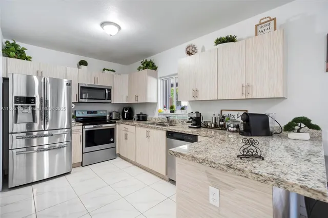a kitchen with granite countertop a sink stainless steel appliances and white cabinets