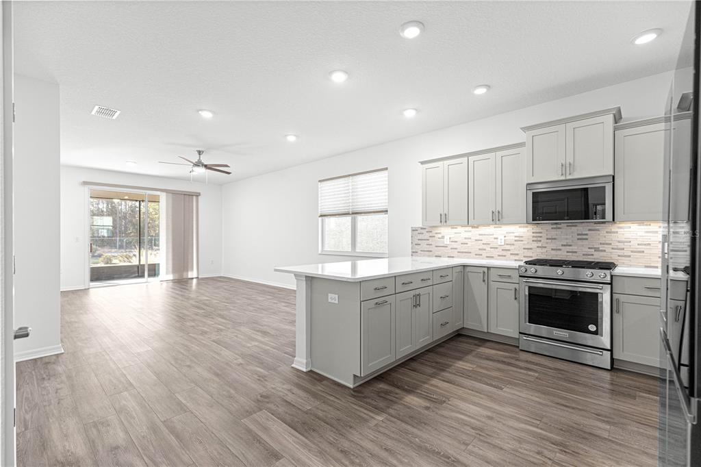 10242 Southwest 99th Lane Ocala, FL 34481 - Photo 13 of 51 a large kitchen with cabinets wooden floor and stainless steel appliances