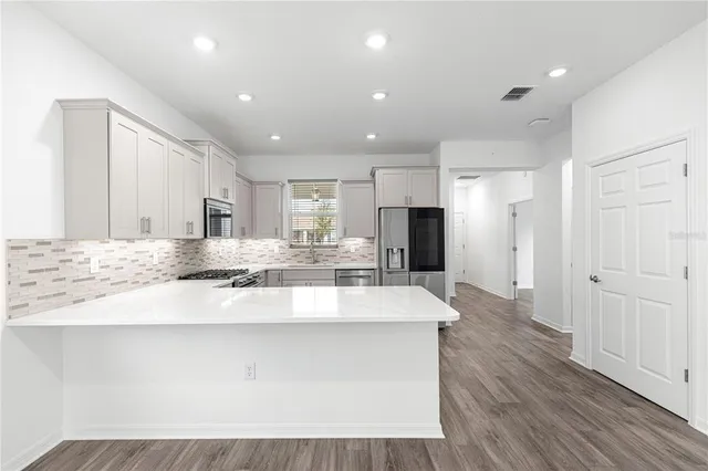 a large kitchen with stainless steel appliances a large counter top a stove and a refrigerator