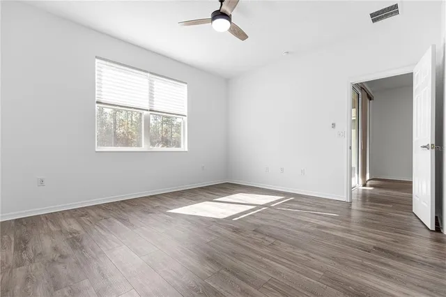 an empty room with wooden floor chandelier and windows