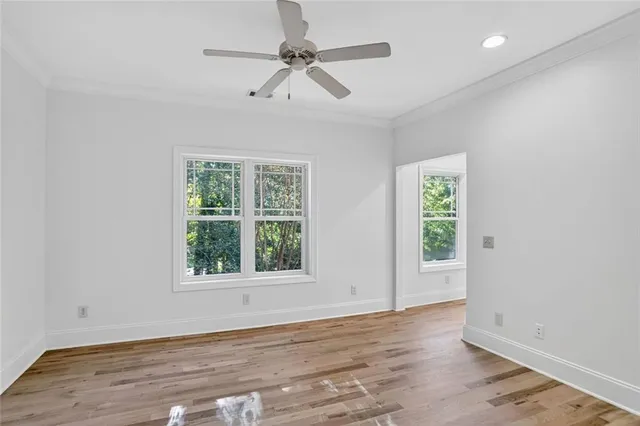 an empty room with wooden floor fan and windows