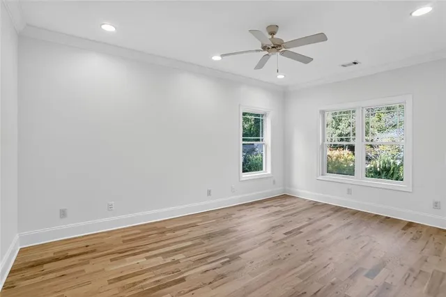 an empty room with wooden floor chandelier fan and windows