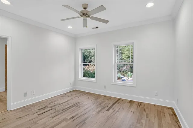 an empty room with wooden floor chandelier fan and windows