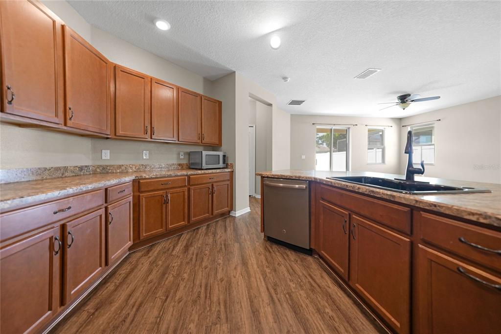 10147 Winding River Road Punta Gorda, FL 33950 - Photo 10 of 33 a kitchen with stainless steel appliances granite countertop wooden cabinets a sink and dishwasher a stove with wooden floors