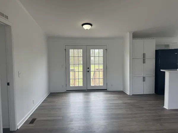 a view of an empty room with a window and wooden floor