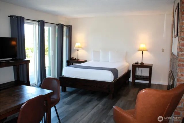 a bedroom with a bed a desk and chair with wooden floor