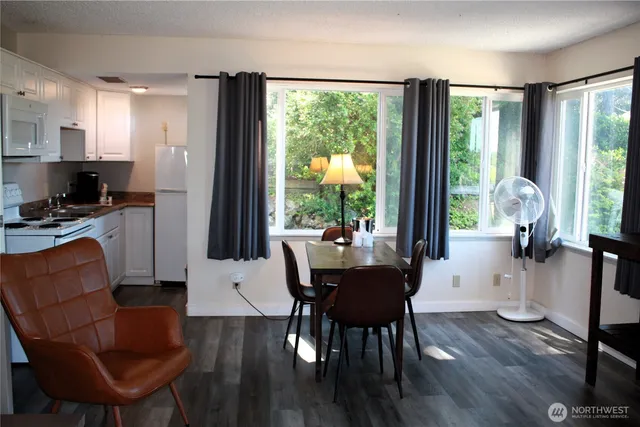 a living room with furniture a large window wooden floor and a rug