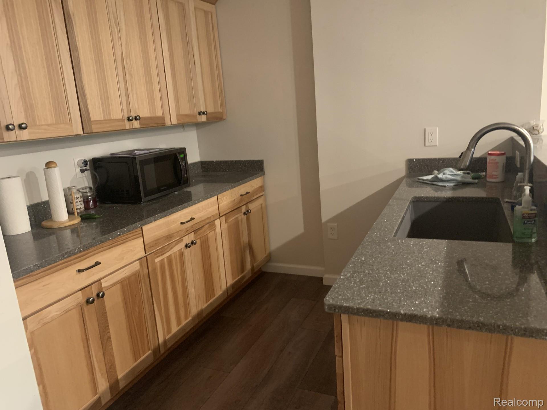 7542 Newberry Road Durand, MI 48429 - Photo 19 of 25 Wood-finish cabinetry with dark hardware, speckled countertops, stainless steel sink, and wood-finish flooring