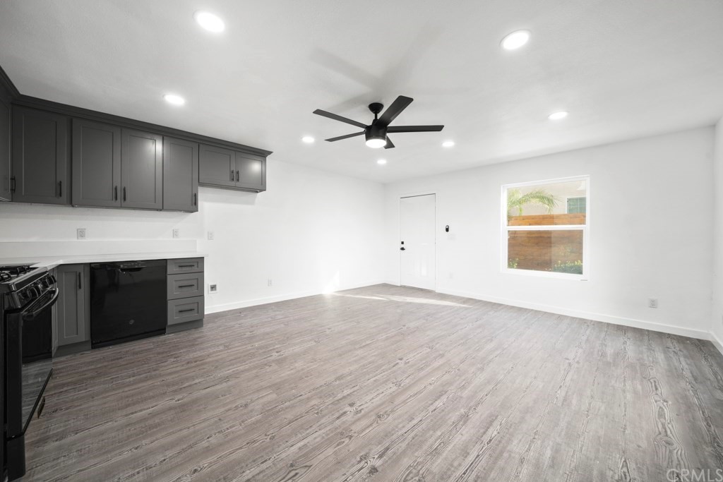 1202 Mahanna Avenue Long Beach, CA 90813 - Photo 14 of 32 an empty room with wooden floor a ceiling fan a kitchen view and a fireplace