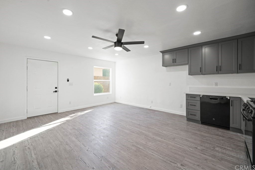 1202 Mahanna Avenue Long Beach, CA 90813 - Photo 8 of 32 an empty room with wooden floor a ceiling fan a kitchen view and a fireplace