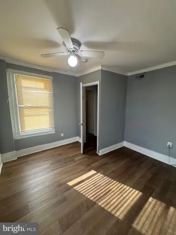 an empty room with wooden floor chandelier fan and windows