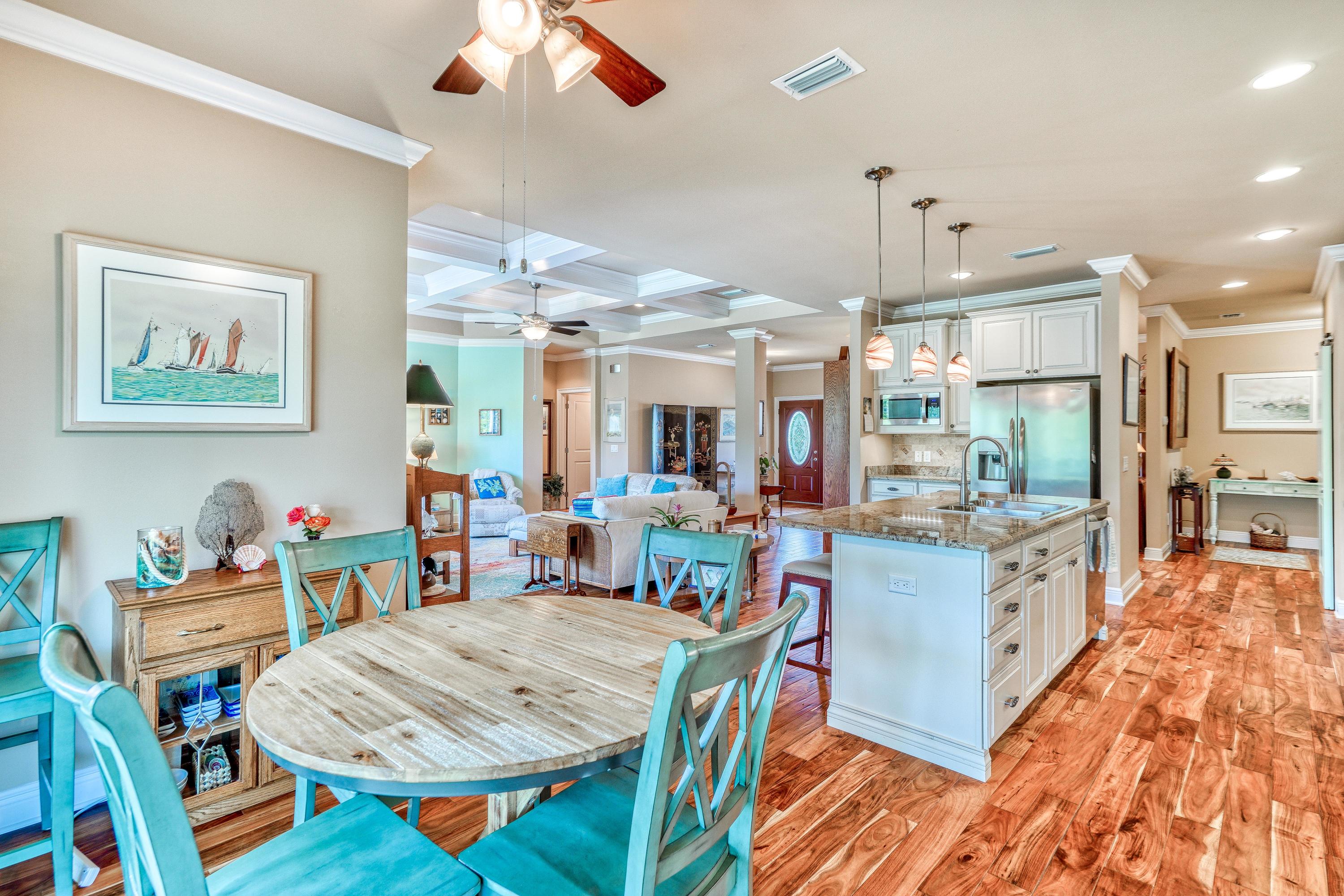 488 Ridge Road Santa Rosa Beach, FL 32459 - Photo 9 of 46 a view of a dining room and livingroom with furniture wooden floor a rug a flat screen tv a painting and a chandelier