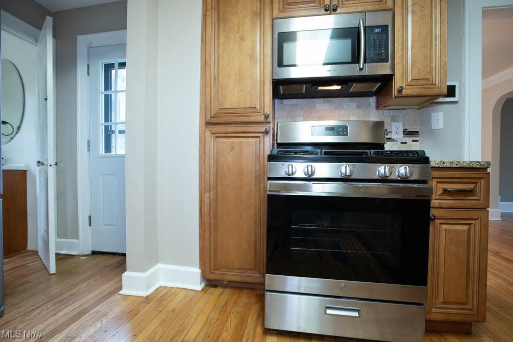 1106 Hillstone Road Cleveland Heights, OH 44121 - Photo 15 of 35 Kitchen featuring light hardwood flooring, backsplash, and appliances with stainless steel finishes