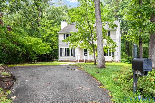 a backyard of a house with plants and large tree