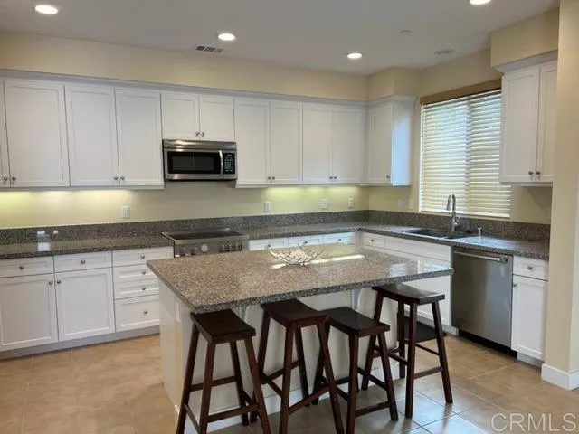 a kitchen with granite countertop a sink and white cabinets