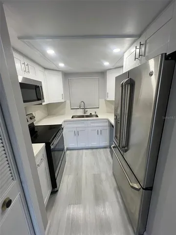 a kitchen with granite countertop a refrigerator a sink a stove a microwave oven and cabinets