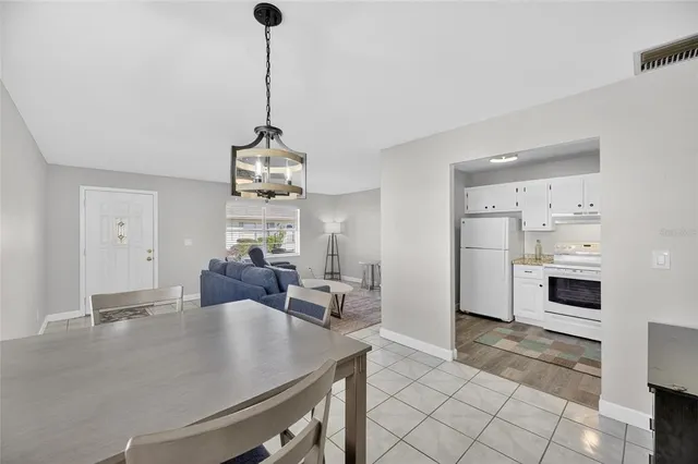 a view of a dining room and a livingroom with furniture wooden floor windows and a chandelier