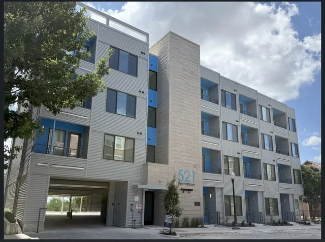 a front view of a building with lot of cars and trees