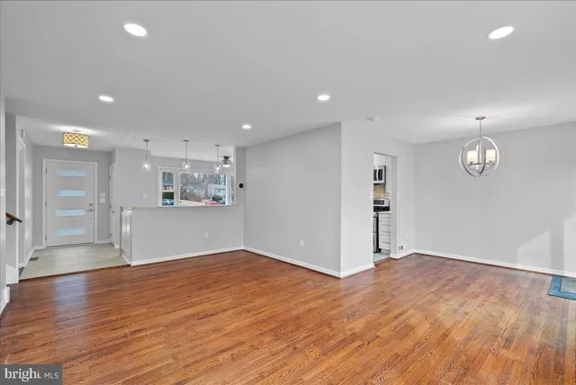 a view of kitchen and empty room with wooden floor