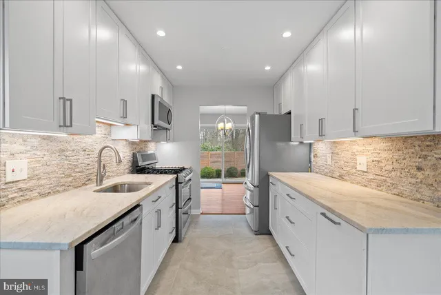 a large white kitchen with stainless steel appliances granite countertop a sink and cabinets