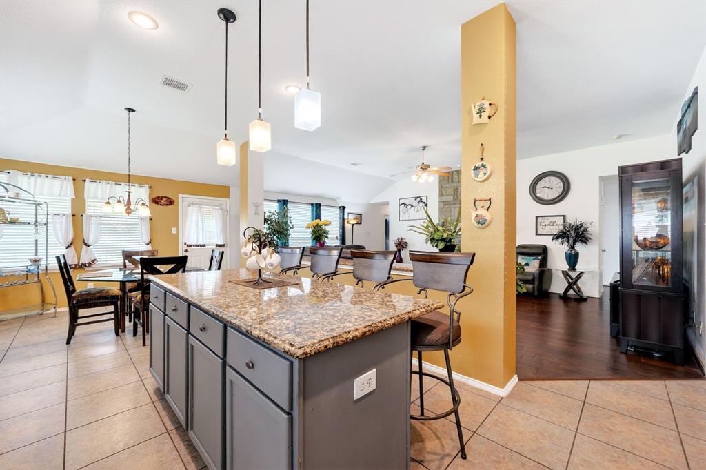 511 Chestnut Trail Forney, TX 75126 - Photo 17 of 32 Kitchen island with a granite-style countertop and seating for three, featuring pendant lighting