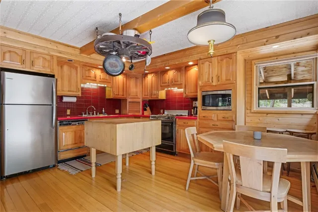 a dining room with stainless steel appliances kitchen island granite countertop a table chairs and a refrigerator