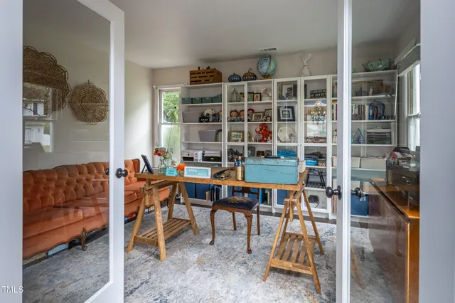 a work room with furniture a rug and a window