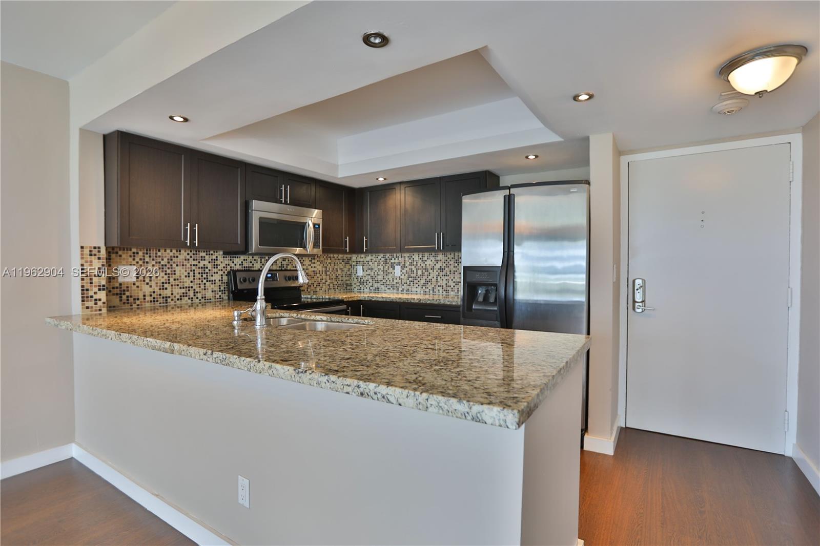 600 Northeast 36th Street, Unit 507 Miami, FL 33137 - Photo 4 of 23 a kitchen with granite countertop a sink and a refrigerator
