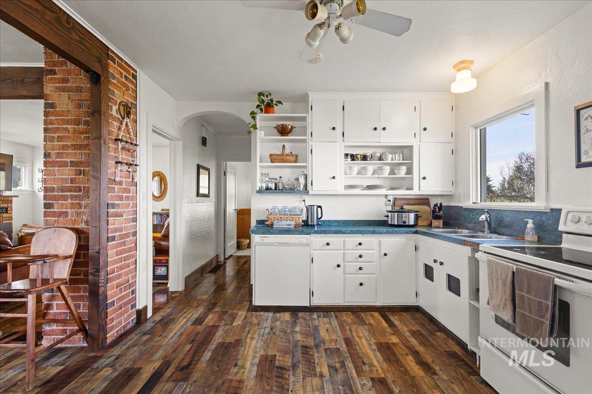 19454 Idaho Road Worley, ID 83876 - Photo 8 of 50 Kitchen with open shelves, white appliances, arched walkways, dark countertops, and dark wood-style floors