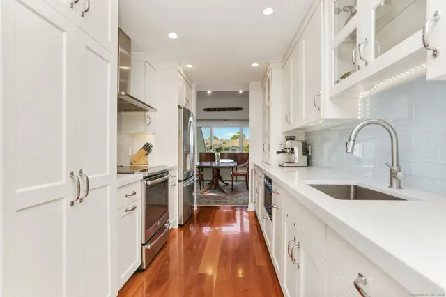 a kitchen with white cabinets appliances and wooden floor