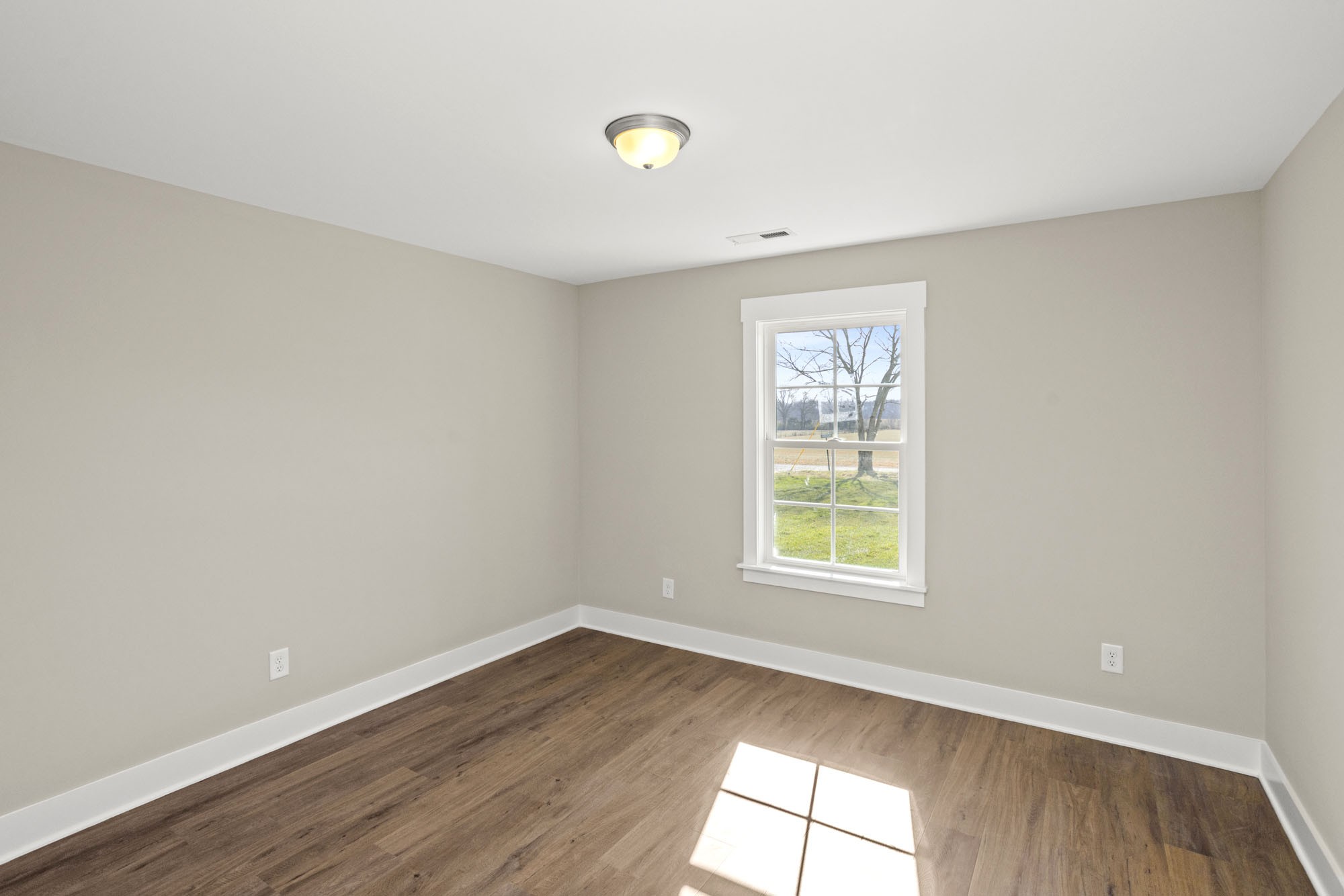 381 Copperas Creek Road Tullahoma, TN 37388 - Photo 16 of 44 an empty room with wooden floor and windows
