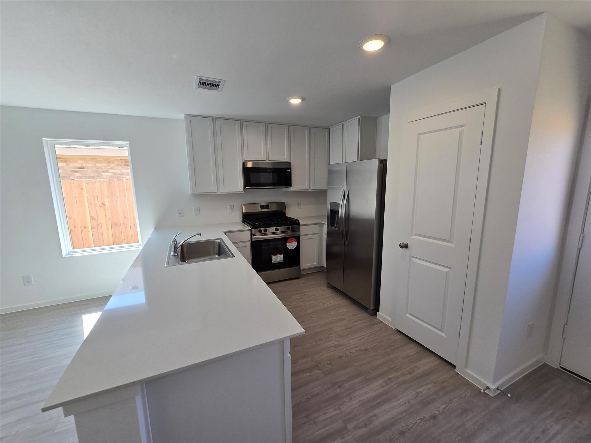 6084 Butler Ridge Drive College Station, TX 77840 - Photo 2 of 12 a kitchen with kitchen island white cabinets and refrigerator