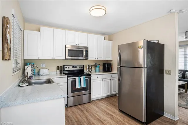 a kitchen with a refrigerator a microwave a sink and cabinets