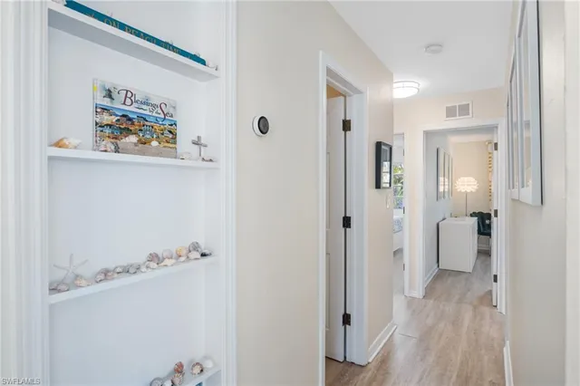 a view of a hallway with wooden floor and a bathroom