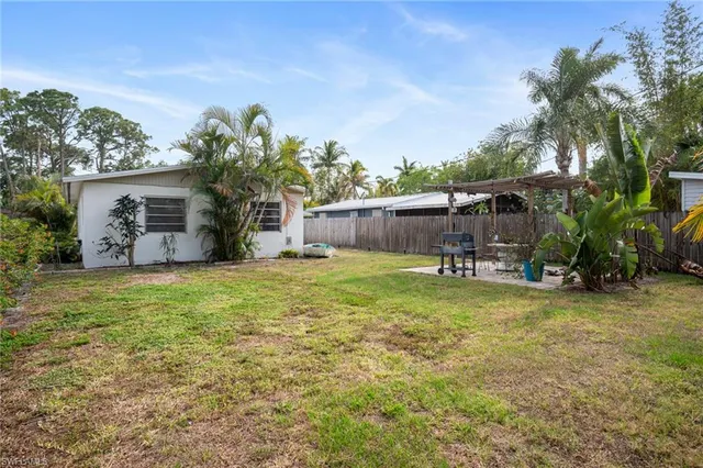 a backyard of a house with table and chairs plants and large tree