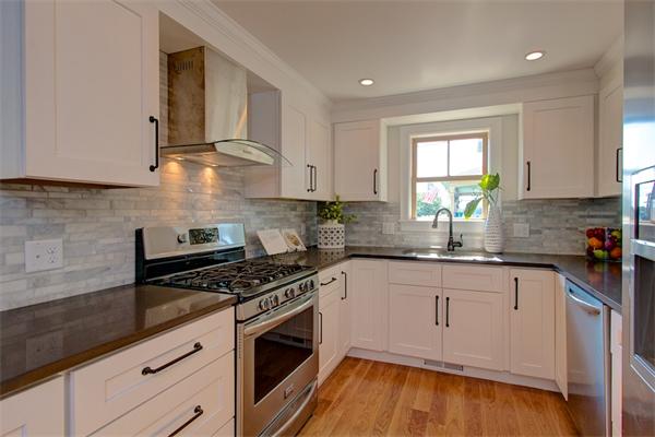 6 Gerring Road Gloucester, MA 01930 - Photo 10 of 22 a kitchen with granite countertop a stove a sink dishwasher and white cabinets with wooden floor
