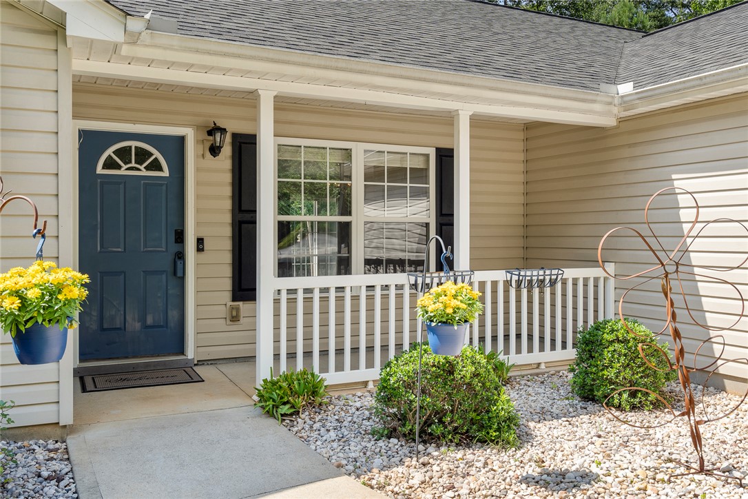167 Mediterranean Avenue Anderson, SC 29621 - Photo 4 of 33 A welcoming entry features a classic porch with white railings, nestled within a low-maintenance gravel landscape.