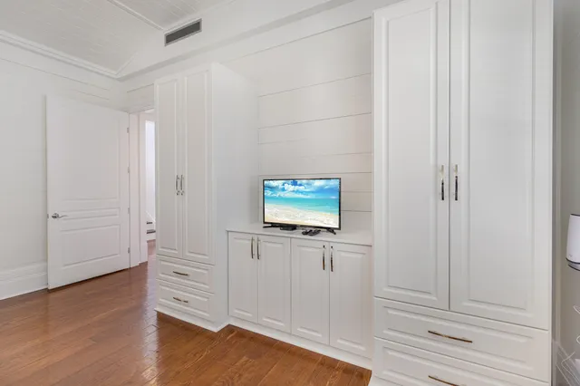 an empty room with wooden floor and cabinet