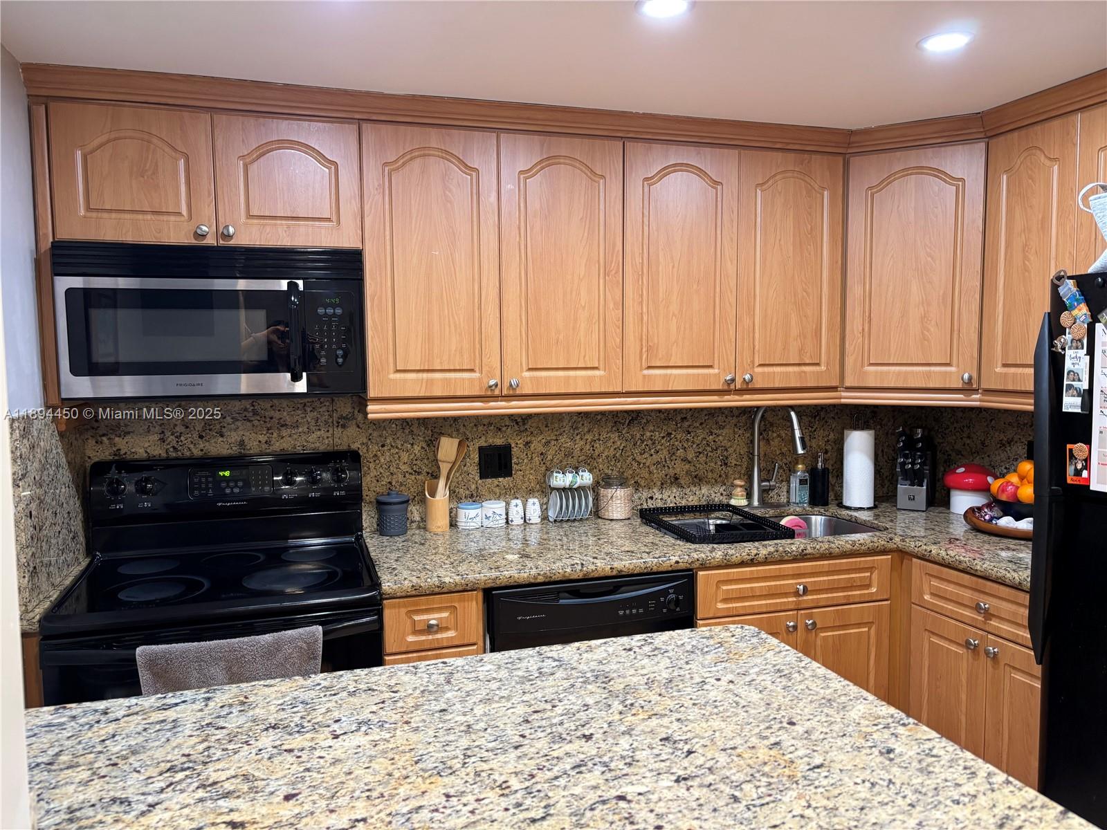 3650 Inverrary Drive, Unit 3YG Lauderhill, FL 33319 - Photo 23 of 38 a kitchen with stainless steel appliances granite countertop a stove top oven microwave and cabinets