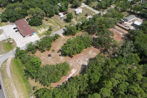 an aerial view of residential house with outdoor space and trees all around