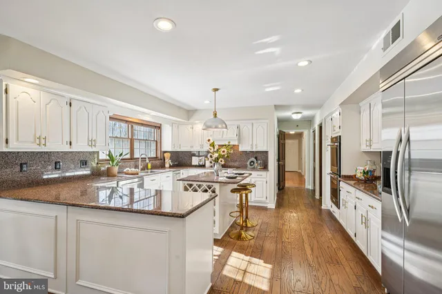 a kitchen with stainless steel appliances kitchen island granite countertop a stove top oven a sink a dining table and chairs