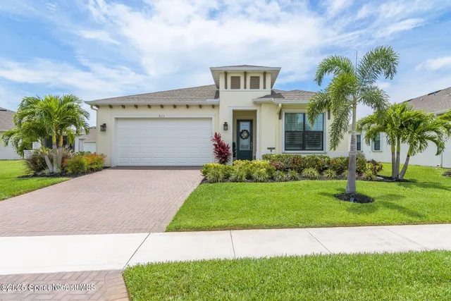 a front view of a house with a garden and palm tree