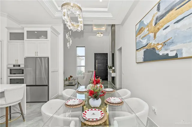 a living room with couches a dining table and a chandelier with kitchen view