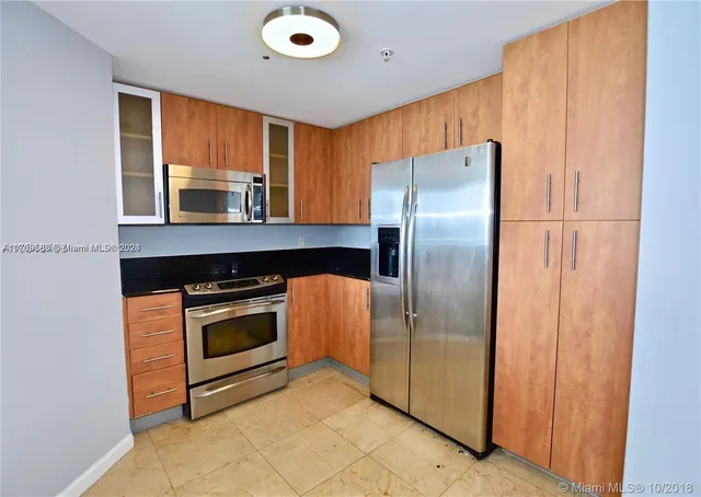 a kitchen with stainless steel appliances granite countertop a refrigerator a stove and a sink